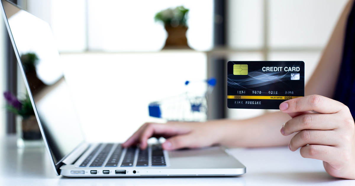 A person holds a credit card they are using to make an online payment to their law firm for legal services.