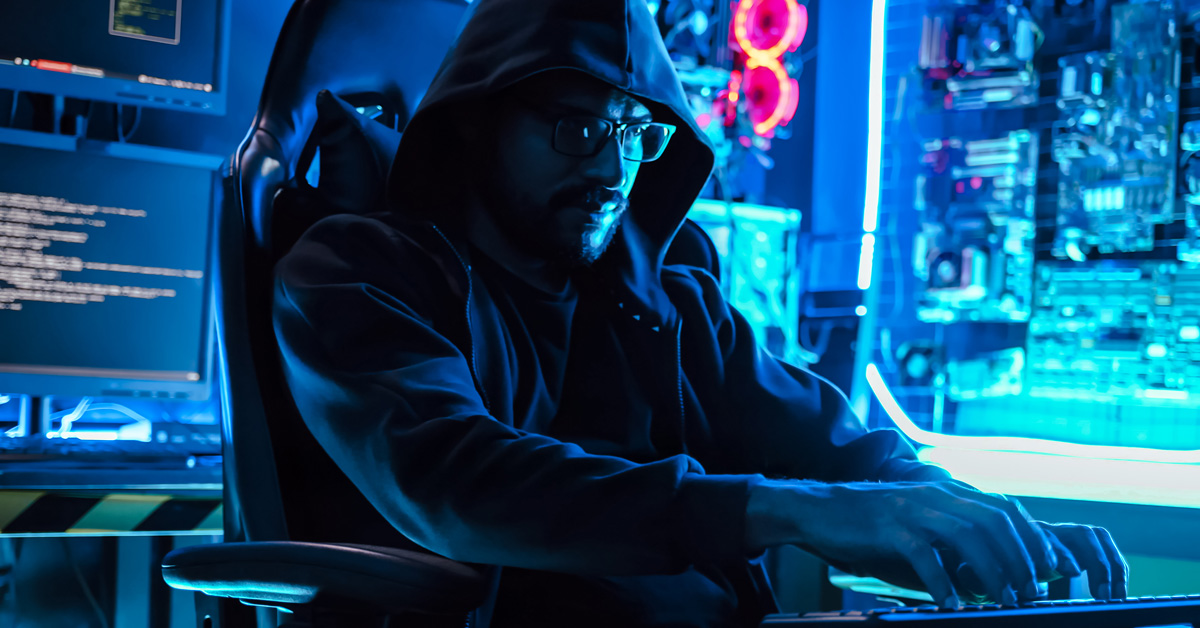 A male hacker sits at his computer as he attempts to hack his way past cybersecurity for a law firm.