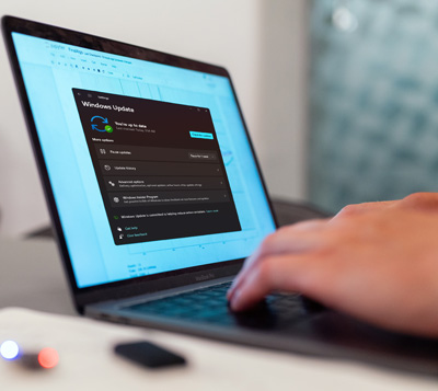 A man's hands are on the keyboard of his laptop while a software update is displayed on his laptop screen.