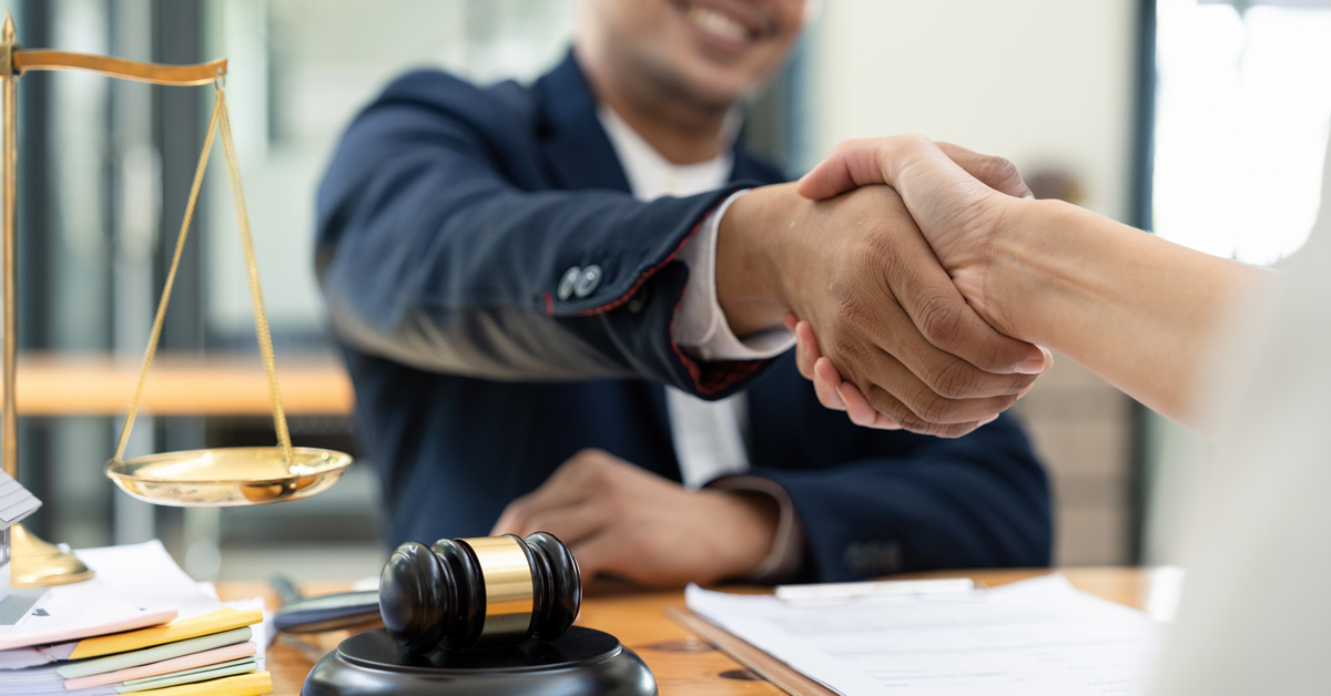 A lawyer shakes hands with a smiling client.